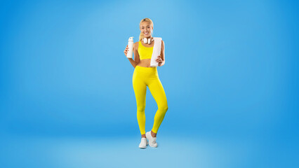 Sporty smiling woman posing at studio with water bottle