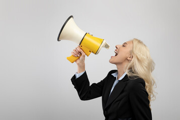 Announcement concept. Businesswoman shouting with megaphone in hands, sharing news over light background
