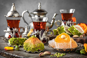 Obraz na płótnie Canvas Oriental sweets. Lukum, pistachio baklava. Fragrant tea. Turkish mood still life. For advertising, window dressing, travel posters and cafes.
