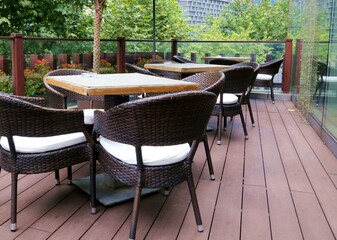 restaurant terrace patio outdoor seating rattan bamboo armchairs with white cushions and wooden...