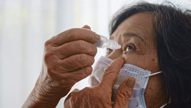 Senior woman is dripping eye drops. Dry eyes. Close-up