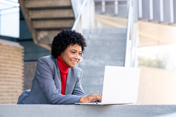 Una elegante mujer afroamericana trabajando con su ordenador portátil en un edificio de oficinas