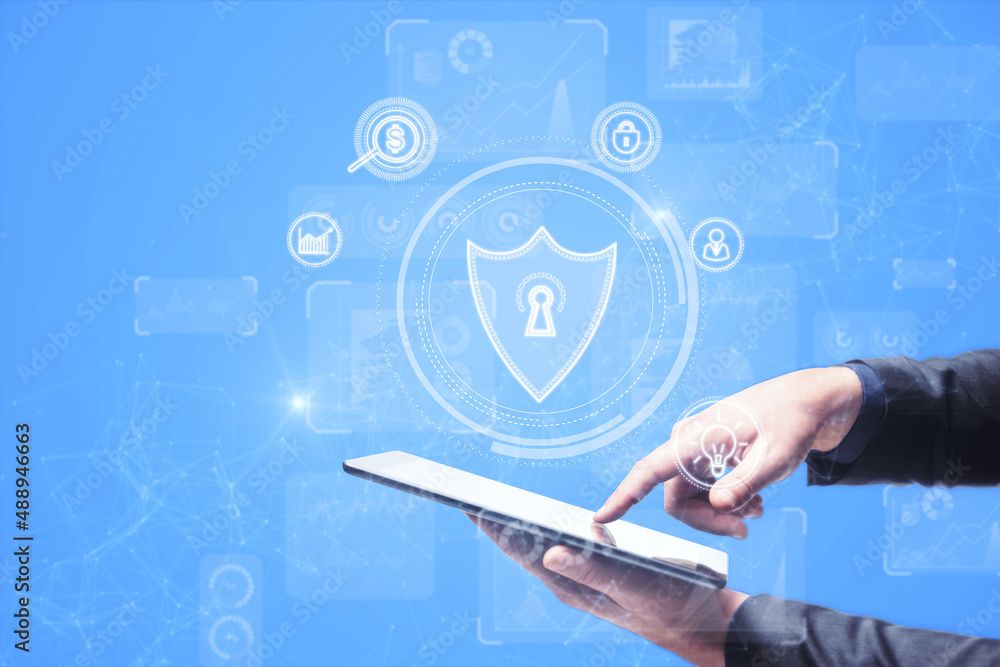 Poster close up of businessman hand pointing at tablet with abstract polygonal shield hologram on blue back