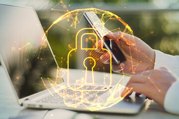 Close up of businessman hands using laptop and smartphone with abstract glowing polygonal sphere with glowing digital padlock on blurry outdoor background. Safety, protect and technology concept. 
