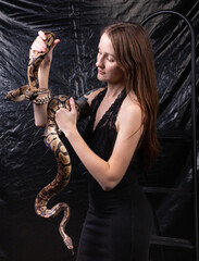 Photo of woman with snakes in hands on dark background