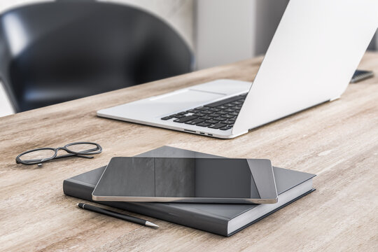 Close up of modern digital tablet on wooden table surface with laptop, notebook and glasses. 3D rendering