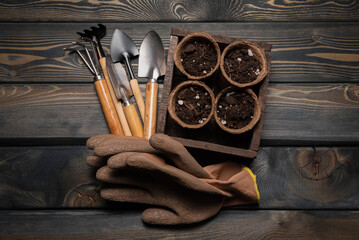 Garden tools, flower pots and gloves on the wooden flat lay table background. Gardening background.