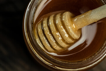 Honey jar and wooden spoon in jar. Bees produce fresh, healthy, honey. Honey background. Beekeeping...