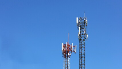 Twin Tower Cellular Base Station. A base station equipped with 4G and 5G cellular wireless communication technology that transmits radio waves to a mobile phone with a clear sky background. 