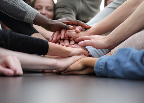 close up. a group of young making a tower of hands on the table