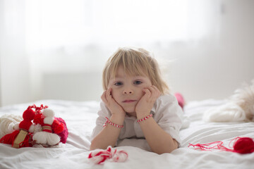 Cute child, blond boy, playing with white and red bracelet