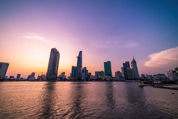Obraz premium View of Bitexco Financial Tower building, buildings, roads, Thu Thiem bridge and Saigon river in Ho Chi Minh city in sunset.