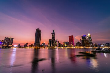 View of Bitexco Financial Tower building, buildings, roads, Thu Thiem bridge and Saigon river in Ho Chi Minh city in sunset.