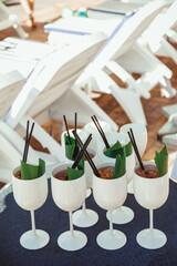white glasses with tropical cocktails decorated with black straws and banana leaves