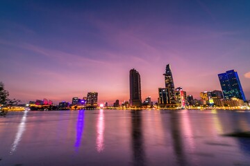 Fototapeta premium View of Bitexco Financial Tower building, buildings, roads, Thu Thiem bridge and Saigon river in Ho Chi Minh city in sunset.