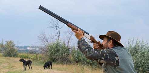 Hunter man in camouflage with a gun during the hunt in search of wild birds or game. Autumn hunting...