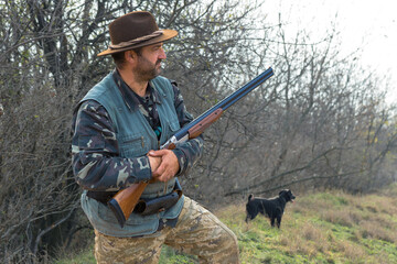 Hunter man in camouflage with a gun during the hunt in search of wild birds or game. Autumn hunting season.