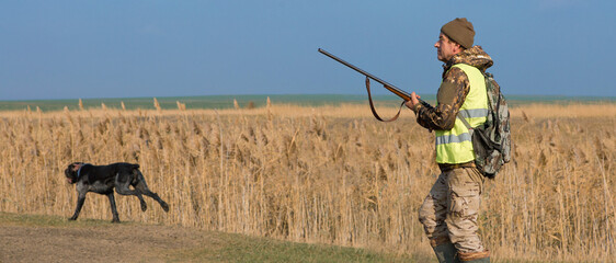 Hunter man in camouflage with a gun during the hunt in search of wild birds or game. Autumn hunting...