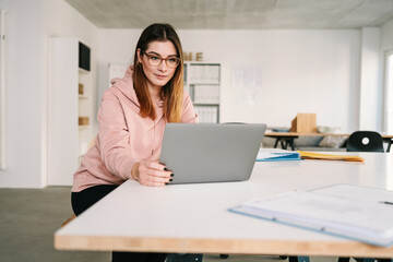 Confident beautiful female freelancer using laptop working at home office