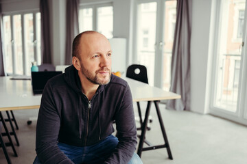 Thoughtful man with receding hairline looking away at home