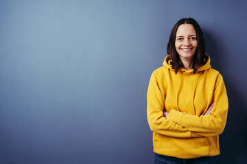 Portrait of smiling woman standing with arms crossed against blue background