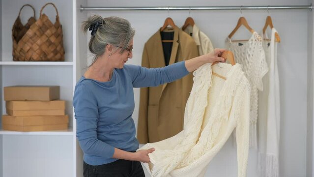 Elderly woman during chooses clothes at home