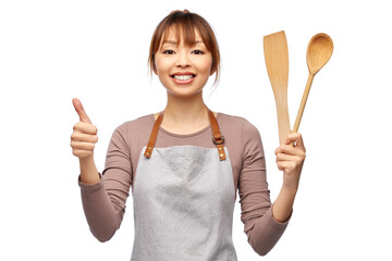 cooking, culinary and people concept - happy smiling female chef in apron with wooden spoon showing...