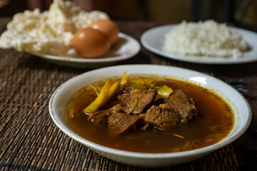 Rawon is a strong rich tasting traditional Indonesian beef black soup served From east java with rice, egg and krupuk on background