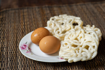 Kerupuk ikan putih is Indonesian traditional deep fried crackers made from starch mixed with flavorings such as fish and eggs,  served in white plate on wooden table. Selective focus