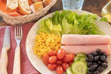 a plate of fresh vegetables with ham on a table