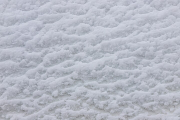 Beautiful winter background with snowy ground. Natural snow texture. Wind sculpted patterns on snow surface