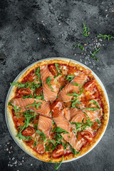 Delicious hot pizza with salmon, red caviar, tomatoes and aragula ready to eat. vertical image. top view. place for text