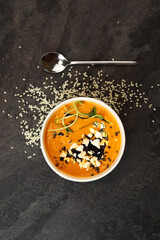 Pumpkin soup with feta cheese and microgreens in a round black eco container on a dark background. Healthy food delivery concept.