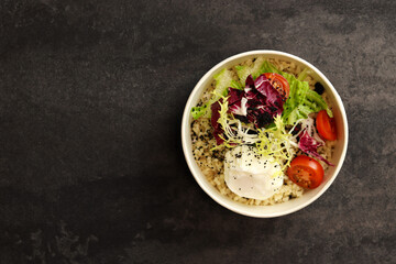Healthy bowl with poached egg, bulgur, tomatoes and lettuce. on a dark background in an eco paper box. Healthy food delivery concept.