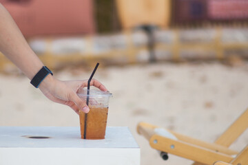 Close-up of a man's hand reaching for a cup of coffee placed on a white table.