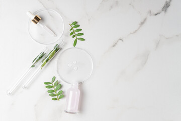 Flat lay of cosmetics serum and and laboratory glassware with fresh leaves on marble background....