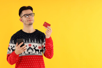 Attractive guy with credit card and phone on yellow background