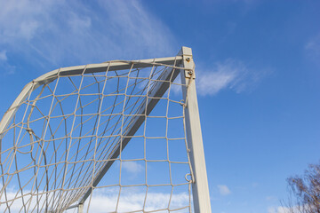 Corner of football goal. Triangle with Net of goal in soccer field at evening time - close up