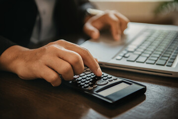 Hand businessman doing finances and calculate on desk about cost at office.