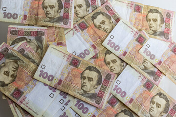 Ukrainian paper money is laid out on a blue background. 100 hryvnia banknotes