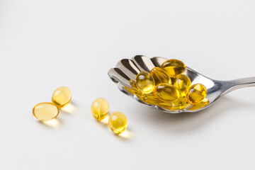 Close up of  oil filled capsules suitable for: fish oil, omega 3, omega 6, omega 9,  vitamin A, vitamin D, vitamin D3, vitamin E with a spoon - Image