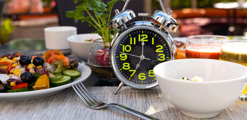 The banner of diet concept with alarm clock  for intermittent fasting during breakfast with a healthy food