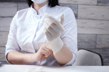 Professional manicurist puts on white medical gloves