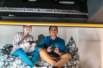 Work hard play hard. Workers Playing computer games man against woman during break in relaxation area at creative startup Office