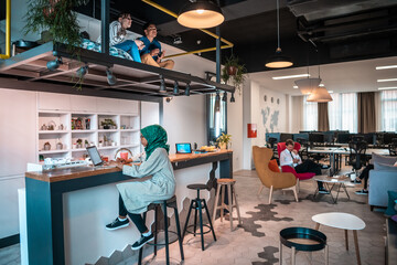 Group of casual multiethnic business people taking break from the work doing different things while enjoying free time in relaxation area at modern open plan startup office