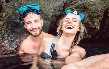 Happy couple taking selfie before entering water cave with waterproof camera - Young people...