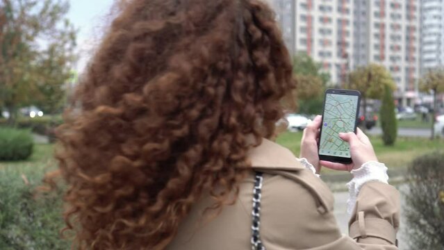 Woman outdoors holding smartphone with city map. A person hand holds a smartphone with an online maps app. GPS concept and internet guide of travel.