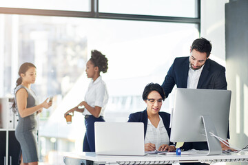 Hes always ready to lend a hand. Cropped shot of two businesspeople working in her office with...