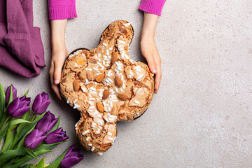 Easter tradition in Italy, Dove Cake topped with icing and almonds. Colomba di Pasqua.  Spring flowers. Top view.
