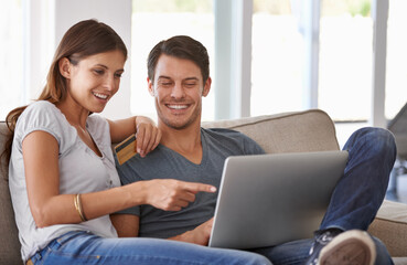We should totally get that. An affectionate young couple doing some online shopping at home.
